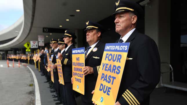  United Airlines pilots hold signs in front of the United Airlines terminal at San Francisco International Airport on May 12, 2023 in San Francisco, California.