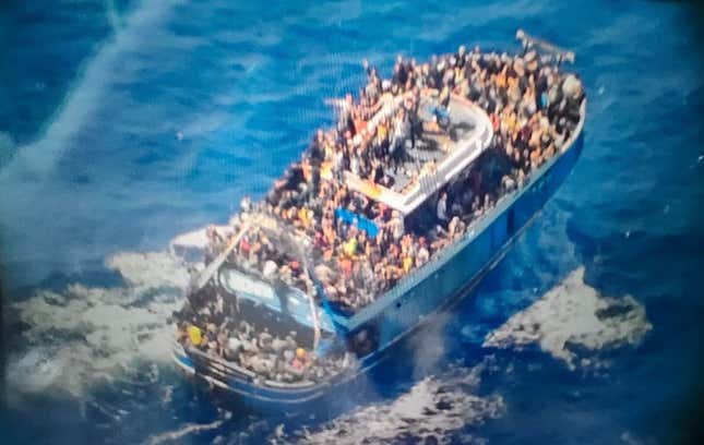 An image provided by the Greek Coast Guard showing a crowded blue fishing boat. Many people are visible aboard