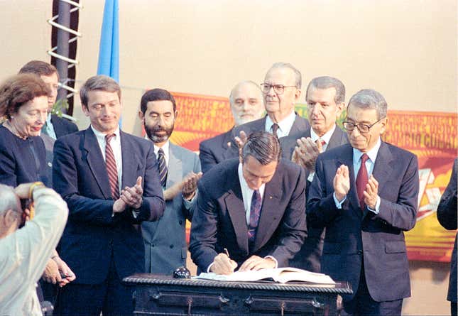 Brazilian President Fernando Collor de Mello, center, is applauded by U.N. Secretary General Boutros Boutros-Ghali, right, as he signs the framework convention on climate change at the United Nations Conference on Environment and Development (UNCED), known as the Earth Summit, in Rio de Janeiro, Brazil, Thursday, June 4, 1992.