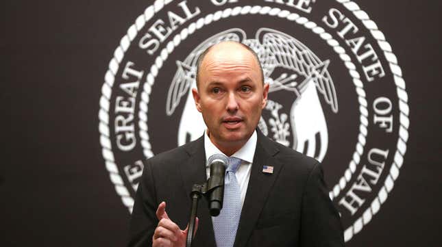 Utah Gov. Spencer Cox standing in front of the state seal.