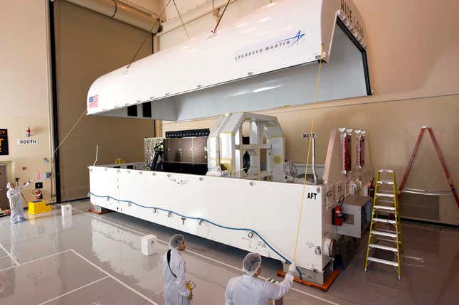 A satellite roughly the same size as Space Vehicle Four is loaded into a transport container.
