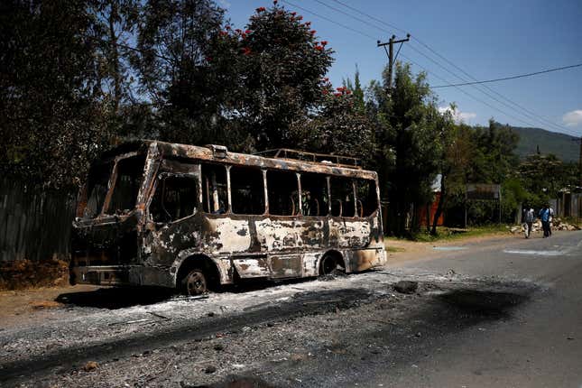 Men walk past a bus that was torched during protests in the town of Sebeta, Oromia region, Ethiopia.
