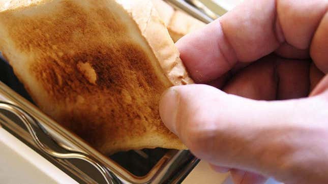 Close-up of person's hand placing toast into toaster