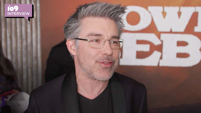 André Nemec, a white man with styled grey hair wearing all black and glasses, speaking on the red carpet at the premiere of Cowboy Bebop.