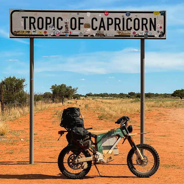 A phot of an electric motorcycle next to a road sign. 