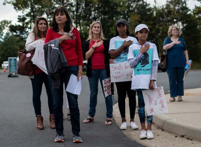 Protesters and activists stand at attention as the national anthem is sung to open a Loudoun County Public Schools (LCPS) board meeting in Ashburn, Virginia, on October 12, 2021