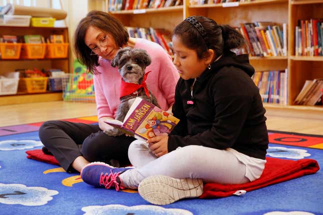Aelane Vasquez, age nine, reads with Leslie Hight, a therapy dog handler for New York Therapy Animals, and Izzy the dog, at Public School 57 in New York. (Reuters/Shannon Stapleton)