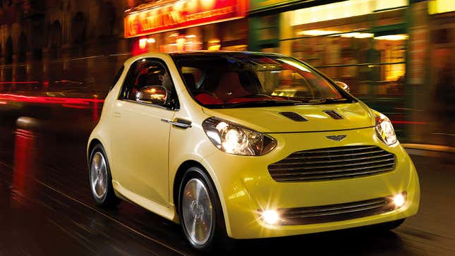 A photo of a white Aston Martin Cygnet driving on a highway at night. 