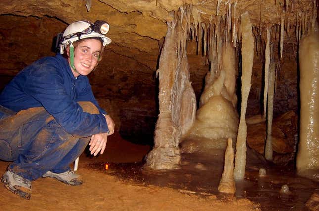 Dr Pickering in a modern cave smiling about the beautiful flowstone on the cave floor.