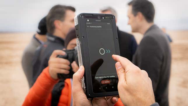 A photo of a person holding up a demo phone to show satellite connectivity 