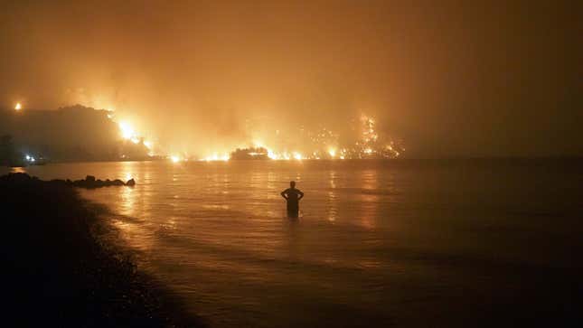 A man watches a wildfire approach the beach in Evia, Greece, in August 2021.