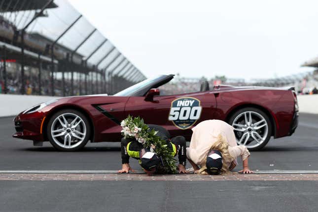 Simon Pagenaud, winner of the 103rd Indy 500, kisses the bricks with his wife.