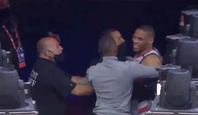 Washington Wizards guard Russell Westbrook is restrained by security after a fan throws popcorn on him.