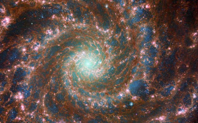 The spiral galaxy is a whirlpool of brown, blue, and pink.