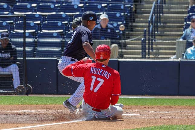 Mar 15, 2023; Tampa, Florida, USA; Philadelphia Phillies first baseman Rhys Hoskins (17) steals home plate in front of New York Yankees pitcher Carlos Gomez (33) during the first inning at George M. Steinbrenner Field.