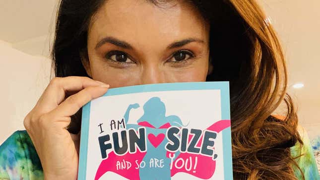 Anjali Bhimani holds up the cover of her self-help book over her face.