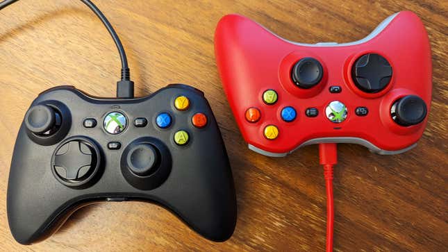 Black and red Xbox 360 replica controllers sit on a wooden table.