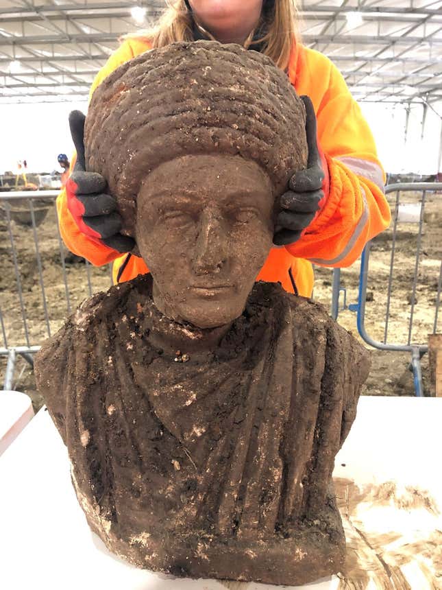 A Roman bust and torso, still caked in dirt.