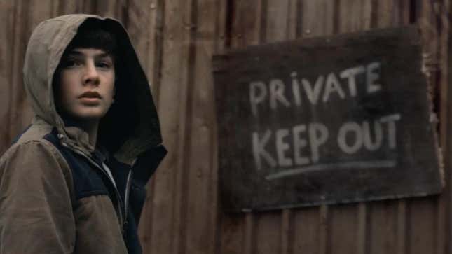A boy wearing a hood next to a "Private, Keep Out" sign
