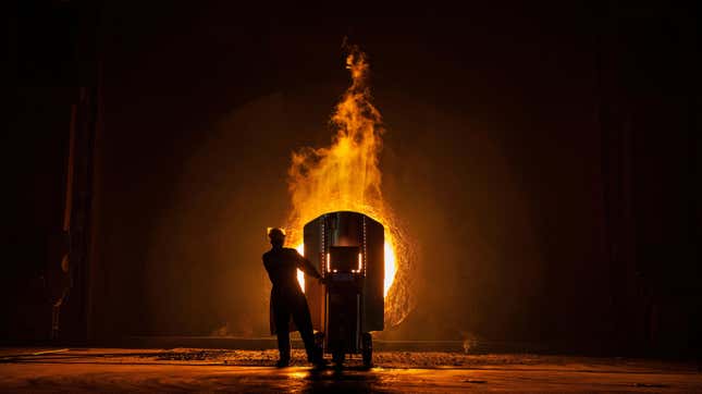 A worker takes samples for quality of molten iron in a steel furnace.
