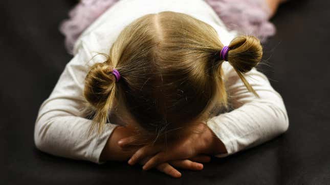 A toddler girl lies facedown on the floor