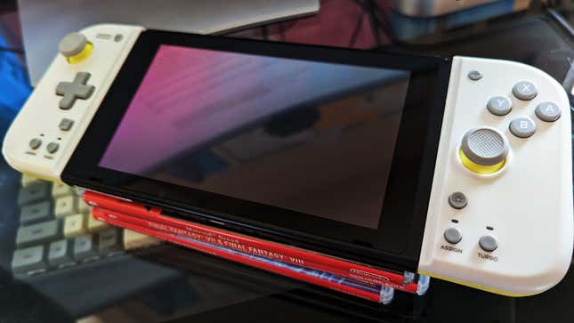 A Nintendo Switch with Hori Split Pad Compact controllers sits on a couple of Switch games.