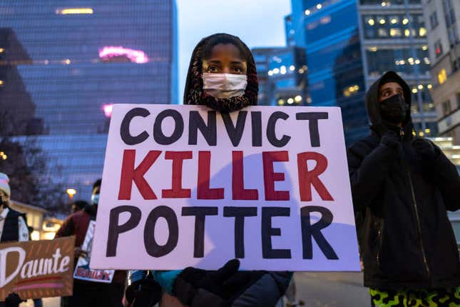 A woman holds a sign reading “Convict Killer Potter” before the start of a march outside the Hennepin County Government Center on November 30, 2021 in Minneapolis, Minnesota. - Jury selection begins today in the trial of Kim Potter, a Brooklyn Center police officer charged with manslaughter in the shooting death of Daunte Wright, when she killed the 20-year-old man during a traffic stop on April 11, 2021.