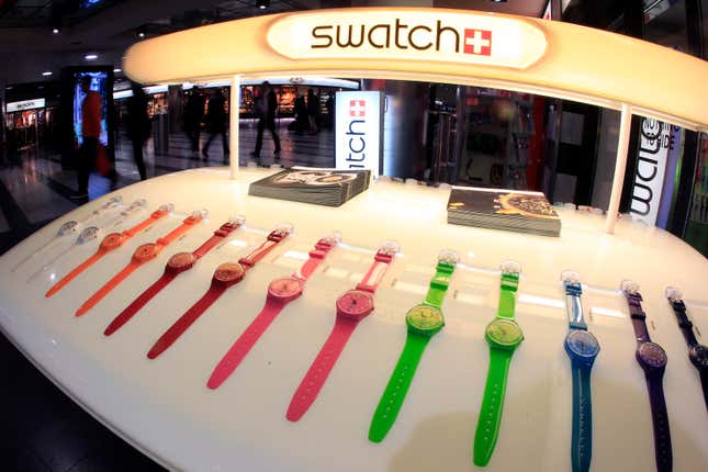 A display of Swatch watches in transparent, orange, red, pink, green, blue, and purple.