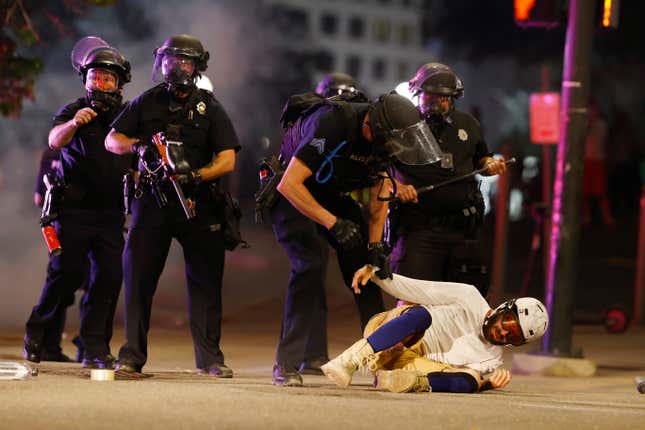 Denver Police Department officers clear a man who fell to the street after they used tear gas and rubber bullets to disperse a protest outside the State Capitol over the death of George Floyd.