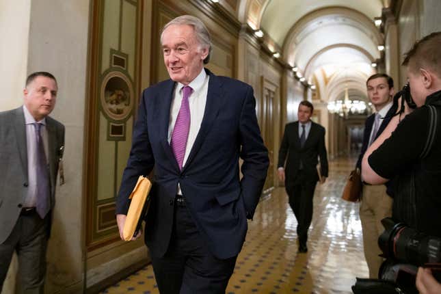 A shot of Ed Markey walking down a hallway in the US Capitol building with one hand in his pocket and the other holding a manila folder.