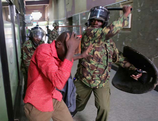 Policemen beat a protester inside a building during clashes in Nairobi.