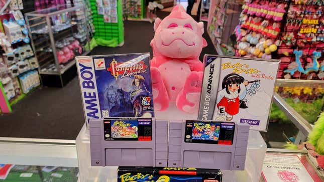 A pink gorilla plush sits on top of a display of retro games.