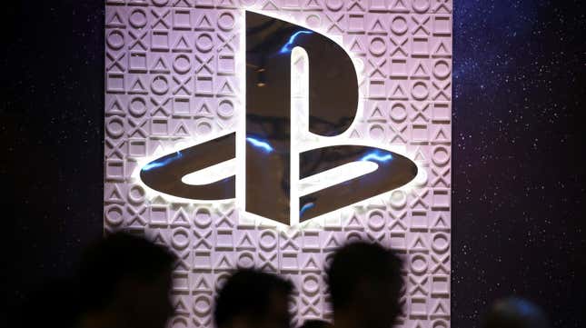 A PlayStation logo is displayed at an event as people walk by. 