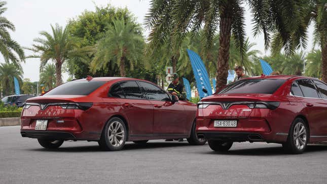 Two of VinFast's internal combustion cars parked under palm trees.