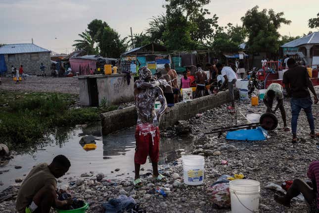 People bathe and do their laundry outside of their homes, due to no running water, in Les Cayes, Haiti, Friday, Aug. 20, 2021, six days after a 7.2 magnitude earthquake hit the area. 