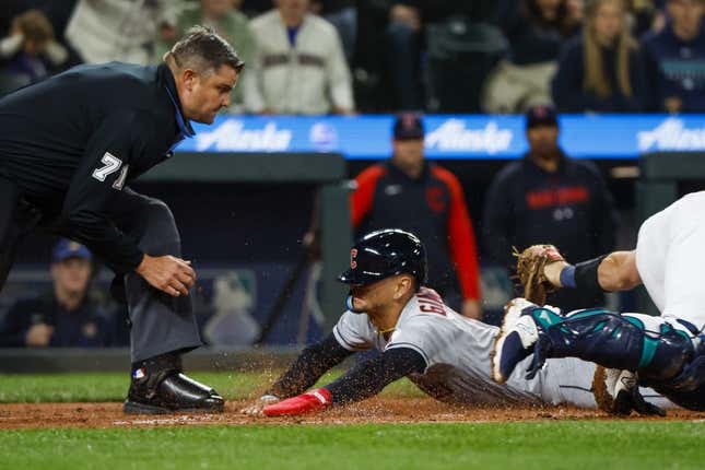Mar 31, 2023; Seattle, Washington, USA; Cleveland Guardians second baseman Andres Gimenez (0) eludes a tag by Seattle Mariners catcher Cal Raleigh (29) following a second throwing error during the second inning at T-Mobile Park. Home plate umpire Jordan Baker (71) watches before making the call.