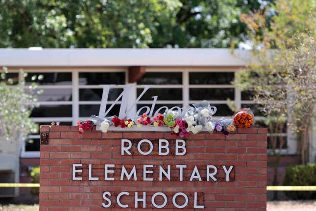 A detail view of flowers are placed around a welcome sign outside Robb Elementary School in Uvalde, Texas.