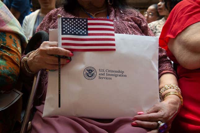 A woman holds the flag and her paperwork as the US Citizenship and Immigration Services welcomes 200 new citizens from 50 countries during a ceremony in honor of Independence Day at the New York Public Library on July 3, 2018, in New York.