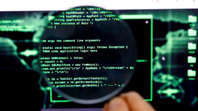 Photo shows a magnifying glass over a screen with computer code.