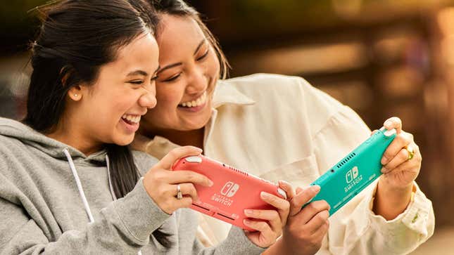Two women hold the Switch Lite, one pink and the other green. 