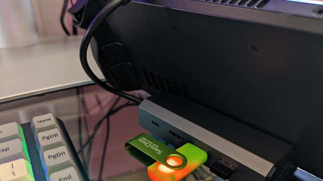 A USB drive is plugged into a dock holding the Steam Dock.