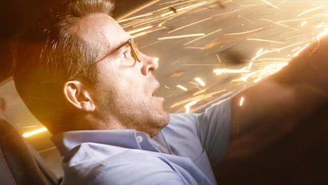 Ryan Reynolds drives with sparks flying toward him in a scene from Free Guy.