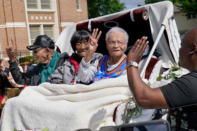 In this Friday, May 28, 2021 file photo, Tulsa Race Massacre survivors, from left, Hughes Van Ellis Sr., Lessie Benningfield Randle, and Viola Fletcher, wave and high-five supporters from a horse-drawn carriage before a march in Tulsa, Okla. Earlier in the month, the three gave testimony in a panel about the massacre in the U.S. House of Representatives. (