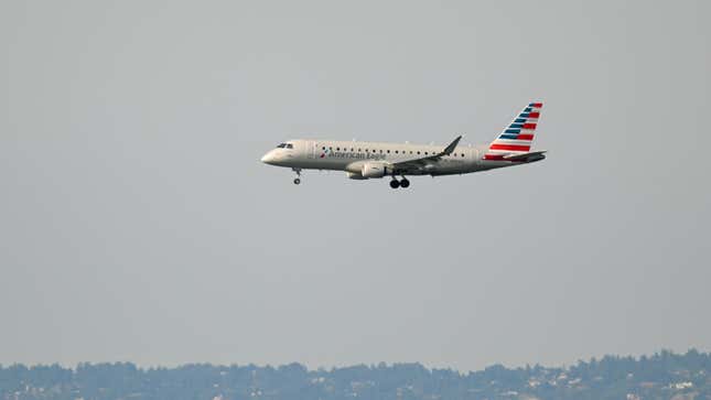 An American Airlines jet in the air preparing to land at an airport. 