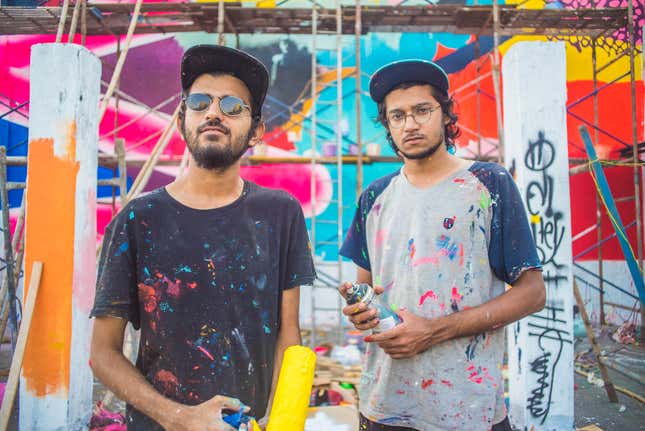 The street artists Do and Khatra in front of their mural at the Sassoon Docks.