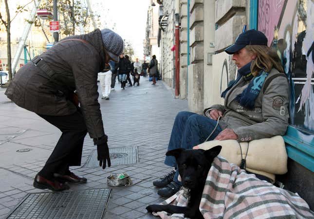 A woman gives money to a homeless man in Marseille.