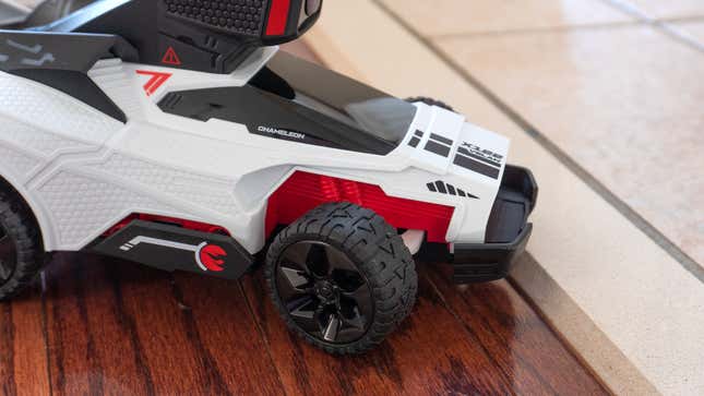 A close-up of the front of the Hot Wheels: Rift Rally RC Chameleon car attempting to traverse a small bump on a floor.
