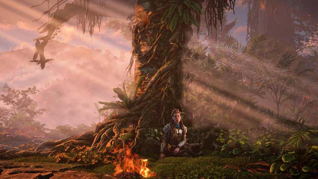 Aloy leans against a tree next to a campfire in Horizon Forbidden West.