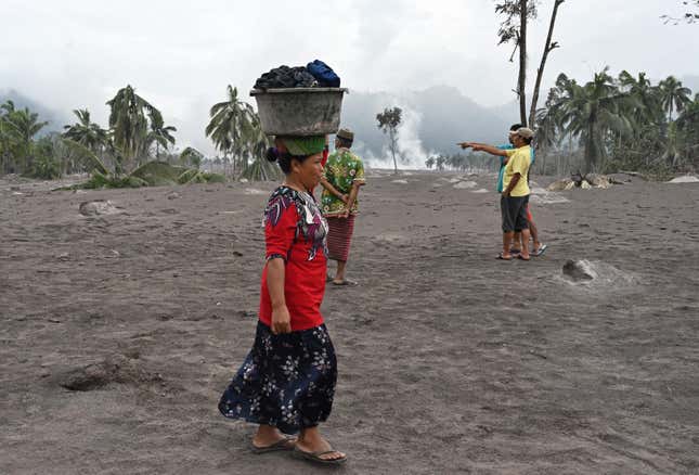 A woman salvages her belongings at the Sumberwuluh village on a field on volcanic ash.