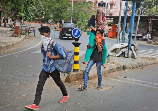 Ramesh Meena from Rajasthan carries his wife, who fractured her leg, on his shoulder, as they leave for their village from Ahmedabad.